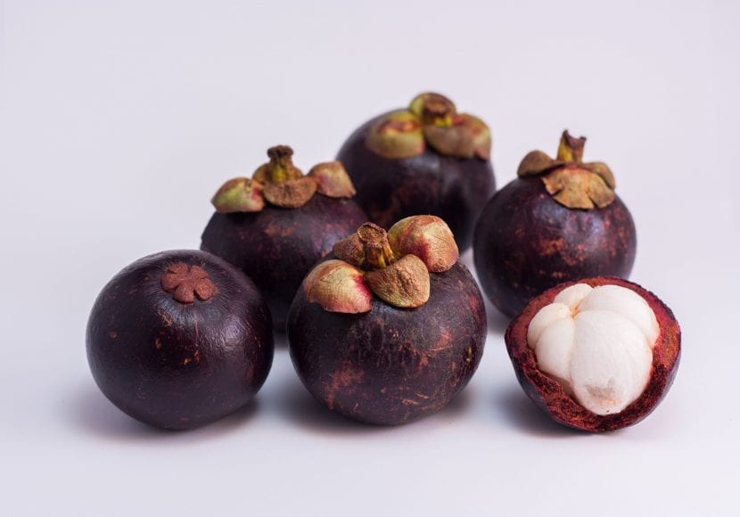 Mangostinos abiertos mostrando los gajos blancos dentro de la corteza púrpura
