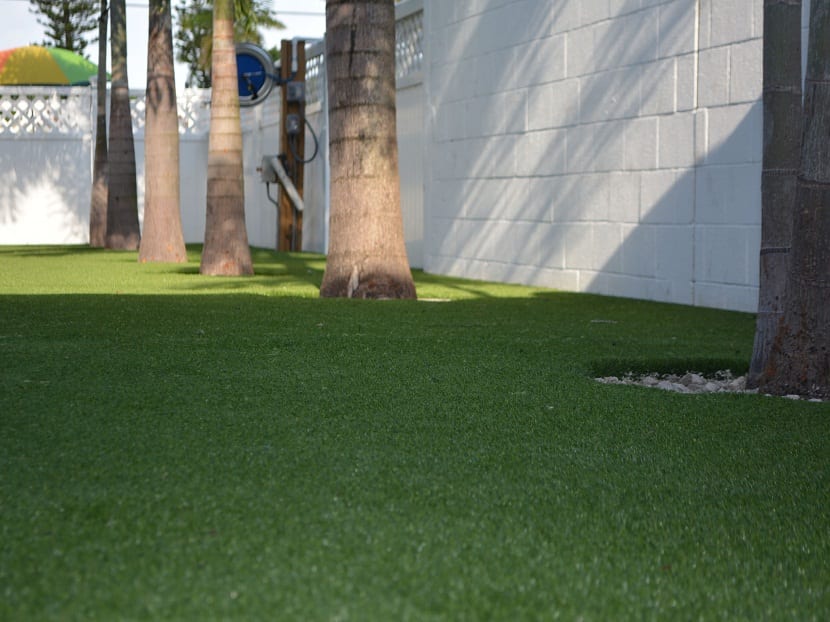 Trabajos de instalación de césped artificial en jardín con arbolado