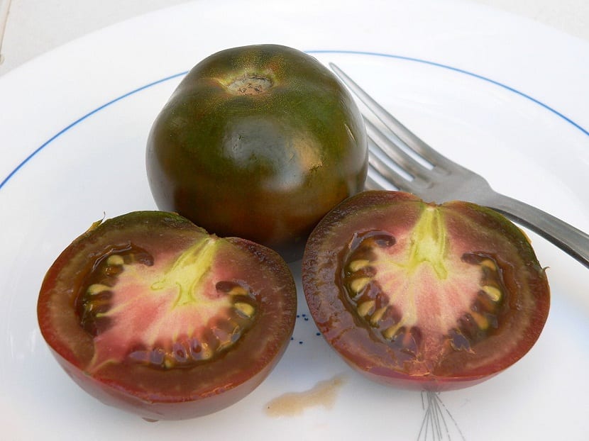 Tomate Kumato partido en dos mostrando la pulpa oscura