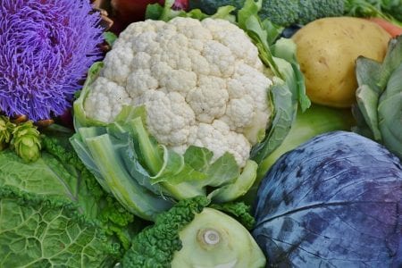 Pella blanca de coliflor rodeada por sus hojas envolventes