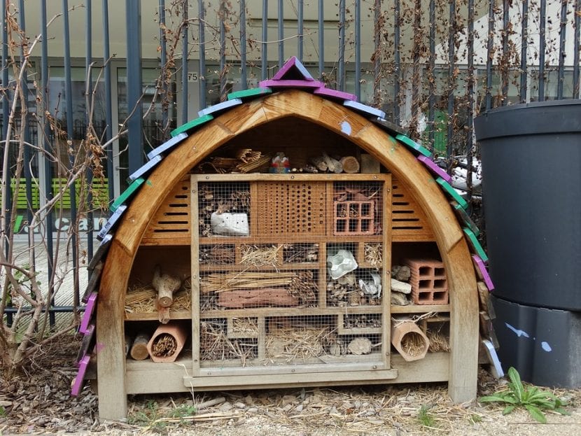 Hotel para insectos de madera con cañas y troncos taladrados