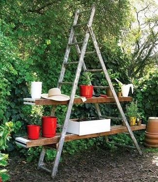 Escalera de madera reutilizada como estantería para macetas en el jardín
