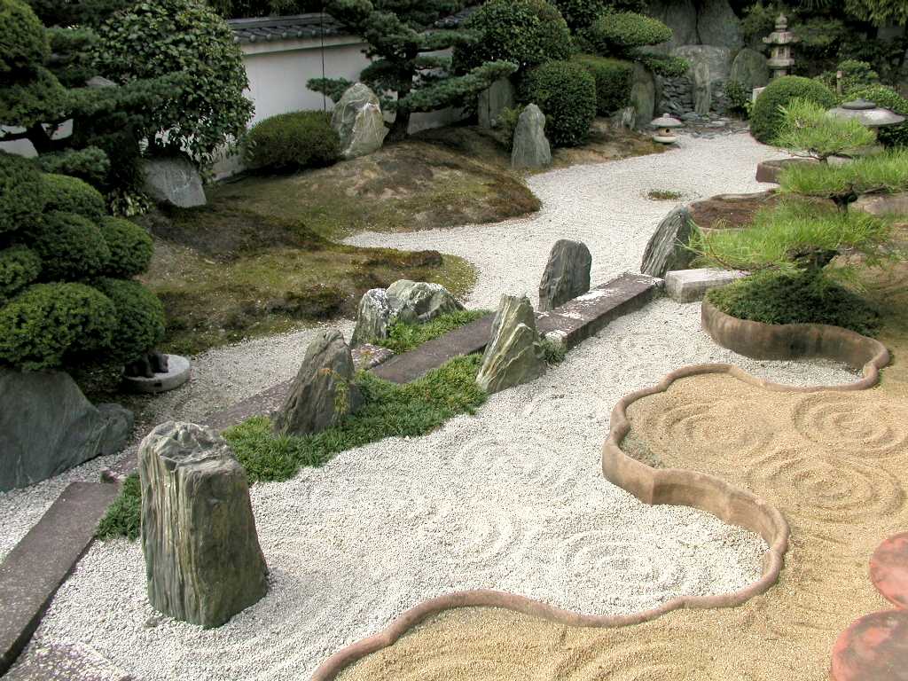 Camino de piedras y vegetación recortada en un jardín de estilo japonés