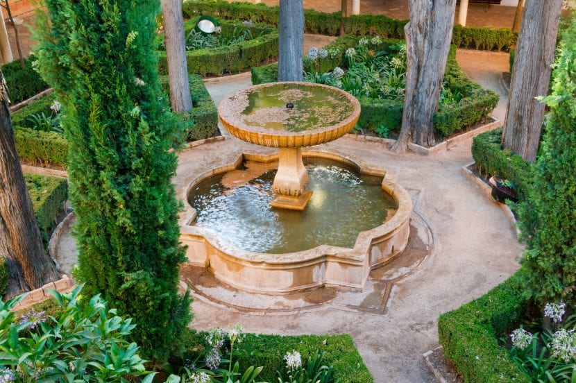 Fuente de piedra en un patio rodeada de vegetación