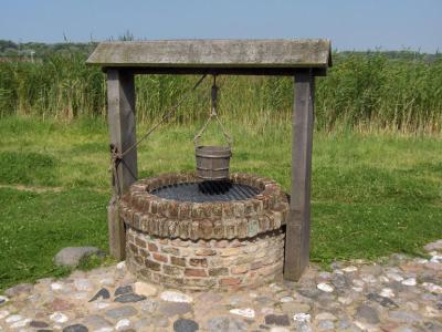Pozo de jardín con brocal de piedra y arco de forja