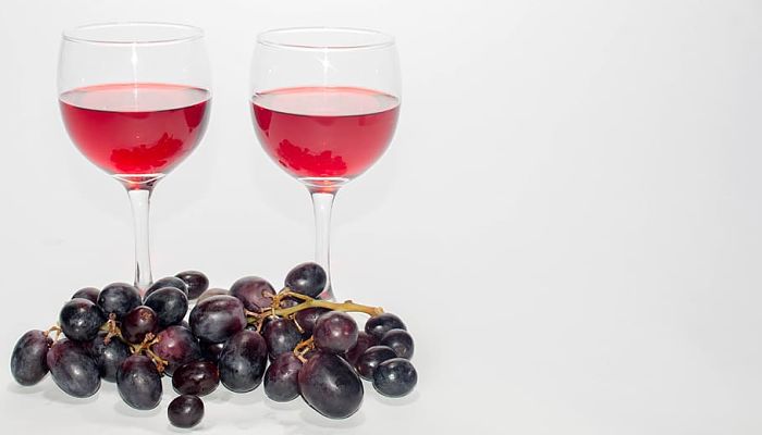 Racimo de uva tinta junto a dos copas de vino