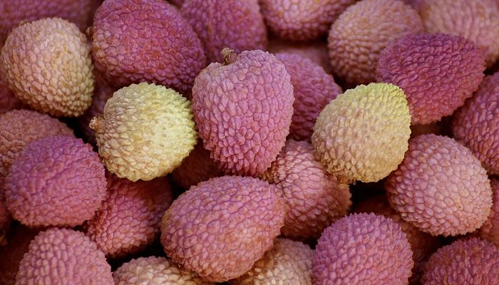 Montón de lichis de piel rosada y rugosa en un puesto de mercado