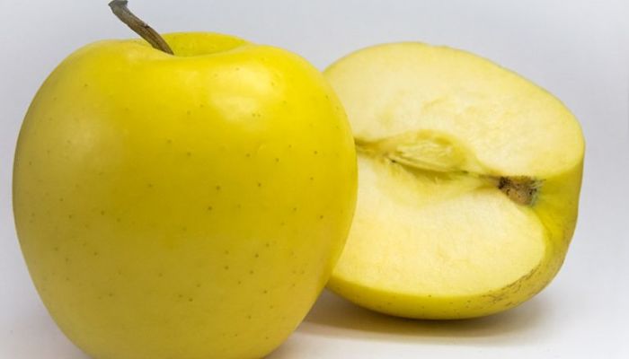 Manzana Golden Delicious entera y partida por la mitad