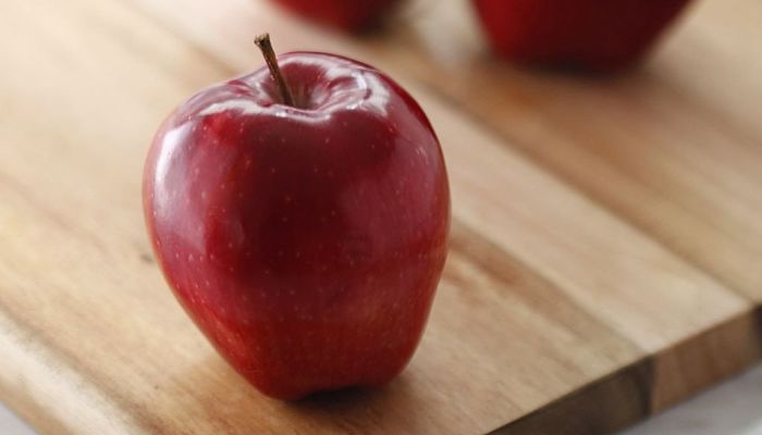Manzana Red Delicious entera sobre una tabla de madera