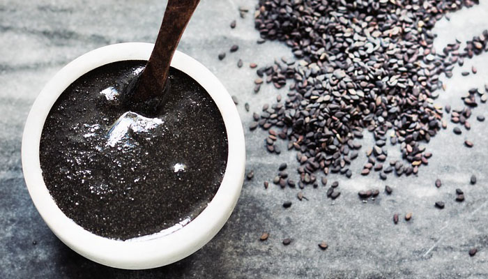 Semillas de sésamo negro junto a un cuenco con pasta de sésamo